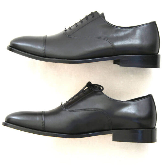 Foto von zwei schwarzen Oxford Glattleder Herrenschuhen mit Zehenkappe. Beide von der Seite nach links zeigend. Modell Oxford Pro