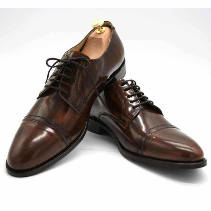Foto von zwei braunen, schwarz changierenden Herrenschuhen einer mit Schuhspanner mit goldenem Knauf, der rechte auf den linken Schuh gestellt - Modell Premium Klasse 329