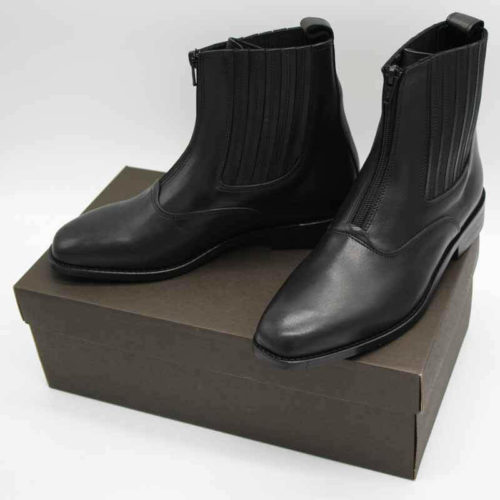 Foto von zwei schwarzen Stiefeletten mit Reißverschluss vorne und flachem Absatz auf dunkelbraunem Schuhkarton. Modell: 411-Schwarze Stiefelette_1