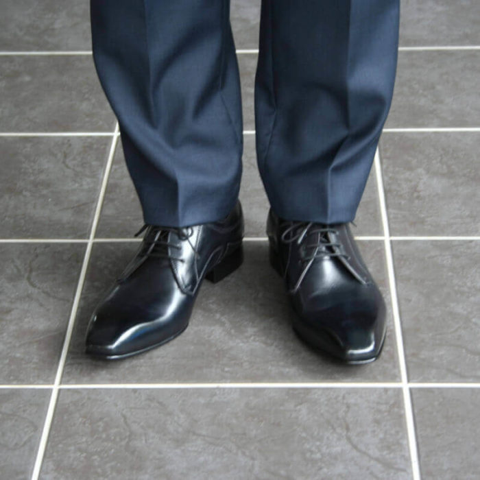 Foto 2 schwarze Herrenschuhe Elegant und schlicht Glattleder. Forntalansicht mit Anzugbeinen in Dunkelblau.