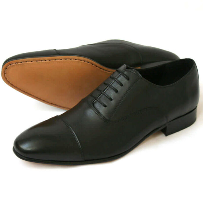 Foto von zwei schwarzen Glattleder Oxford Herrenschuhen nach links zeigend - ein Schuh liegt auf der Seite, so dass die Sohle zu sehen ist. Modell Erste Wahl