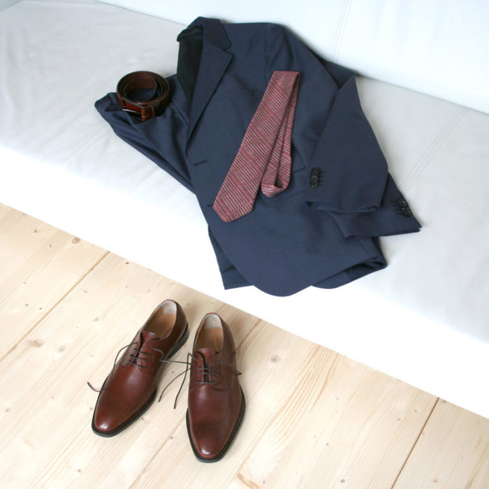 Foto-Nussbraune Business Herrenschuhe_auf Holzboden-dabei Anzug, Krawatte und Gürtel auf Couch