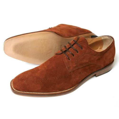 Foto: Zwei cognacfarbene Rauleder Herrenschuhe mit dezenter Verzierung, breiter Sohle und heller Naht. Modell: Lässige Eleganz. Beide Schuhe zeigen nach links. Ein Schuh liegt auf der Seite, so dass die Sohle zu sehen ist.