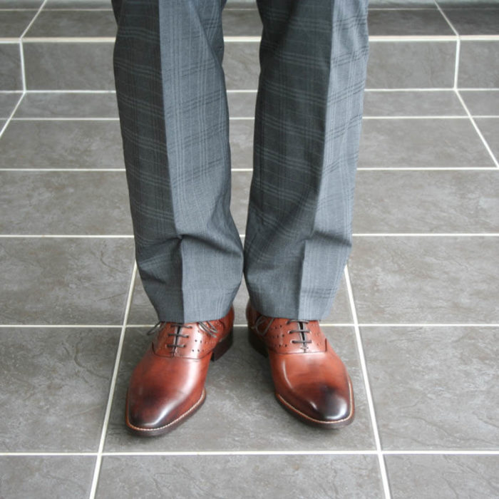 Photo-Men`s business shohes-Sporty elegant-_Oxford_in Cognac with hole pattern_2 shoes with gray suit - only legs-front view