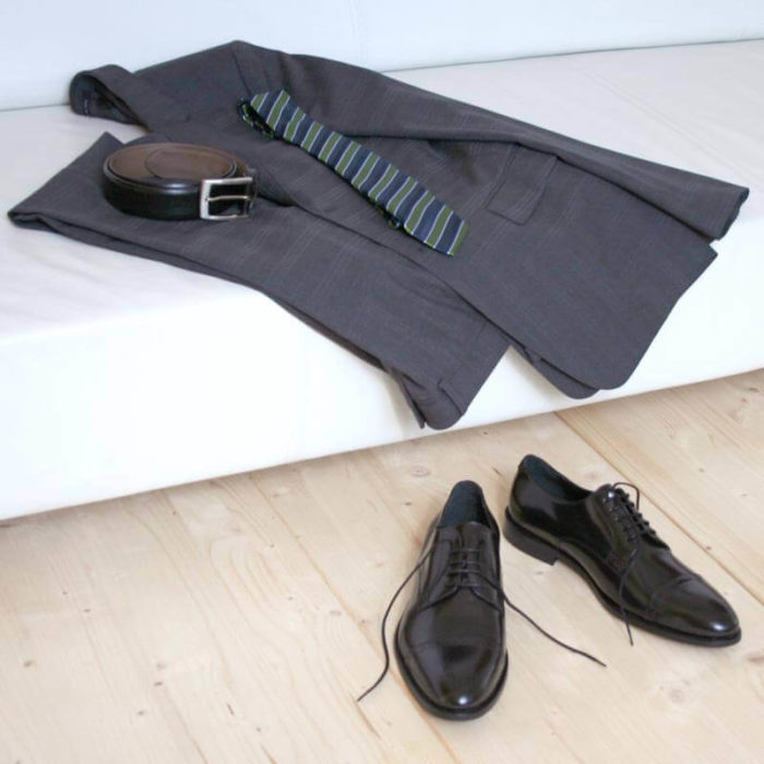 Klassischer Herrenschuh aus schwarzem, poliertem Leder mit grauem Anzug auf Couch 5